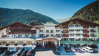 Ansicht des Familienhotels Alpenhotel Kindl in Tirol im Sommer. Das Familienhotel ist umgeben von der schönen Tiroler Bergwelt.