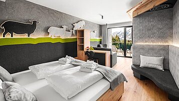 Gemütlich eingerichtetes Elternschlafzimmer "Glückspilz" mit großer Fensterfront im Familienhotel Allgäuer Berghof in den Allgäuer Alpen.