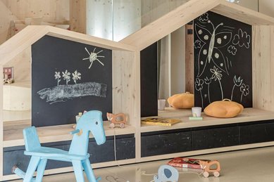 Schaukelpferd und Holzspielhäuschen im Kinderspielbereich des Familienhotels Engel Gourmet & Spa