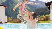 Papa und Tochter planschen im Pool vom Familienhotel Kaiserhof Tiroler Zugspitzarena.