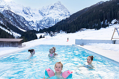 Kinder schwimmen im Außen-Pool im Winter.