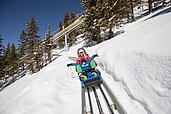 Mutter und Kind rodeln voller Freude die Rodelstrecke hinunter im Familienurlaub im Familienhotel Galtenberg Family & Wellness Resort in Tirol.