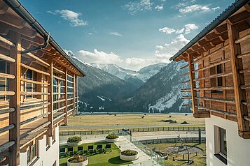 Blick vom Balkon auf die Landschaft und das Nebengebäude im Familienhotel Almfamilyhotel Scherer in Tirol.