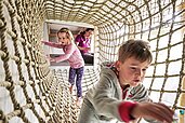 Zwei Kinder klettern im Indoor-Spielplatz in einem Netz im Familienhotel Amiamo im Salzburger Land