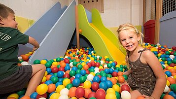 Zwei lachende Kinder spielen ausgiebig im Bällebad im Familienhotel Spa- & Familien-Resort Krone im Allgäu.