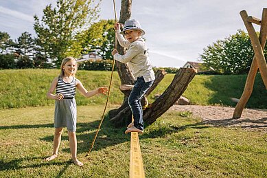 Das Mädchen übt sich auf der Slackline des Spielplatzes vom Familienhotel Strandkind.