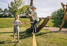 Das Mädchen übt sich auf der Slackline des Spielplatzes vom Familienhotel Strandkind.