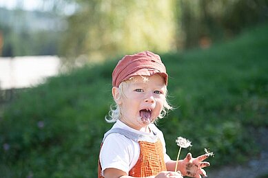 Kleine Mädchen hat eine Blume in der Hand die sie im Garten des Familienhotels Landhaus zur Ohe im Bayerischen Wld gepflückt hat.