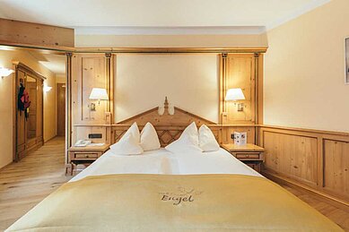 Gemütliches Doppelbett in einer 2-Raum Suite im Familienhotel Engel Gourmet & Spa in Südtirol.