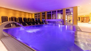 Indoor Therme mit Ambientebeleuchtung und Liegen zum Entspannen im Familienhotel Galtenberg Family & Wellness Resort in Tirol.