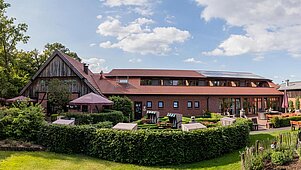 Außenansicht des Familienhotels Landhuus Laurenz mit gemütlicher Terrasse und vielen Sitzmöglichkeiten rund um das Haus.