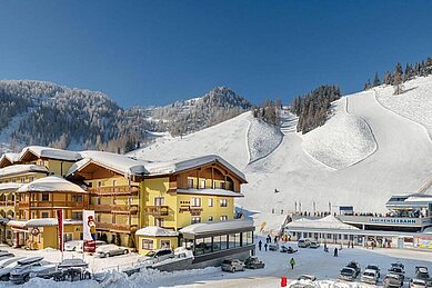 Das Familienhotel Zauchenseehof im Salzburger Land umgeben von einer verschneiten Landschaft. Das Hotel liegt direkt am familienfreundlichen Skigebiet.