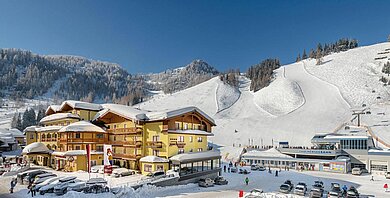 Das Familienhotel Zauchenseehof im Salzburger Land umgeben von einer verschneiten Landschaft. Das Hotel liegt direkt am familienfreundlichen Skigebiet.