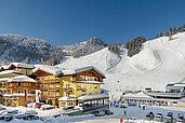 Das Familienhotel Zauchenseehof im Salzburger Land umgeben von einer verschneiten Landschaft. Das Hotel liegt direkt am familienfreundlichen Skigebiet.