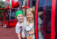 Zwei fröhliche Kinder in roten Gondel-Spielgeräten auf dem Outdoor-Spielplatz des Hotel Engel im Schwarzwald