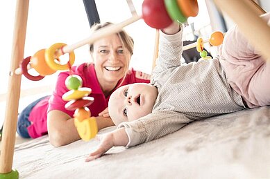 Kleinkind spielt in der Babybetreuung des Allgäuer Berghofs mit der Kinderbetreuuerin.