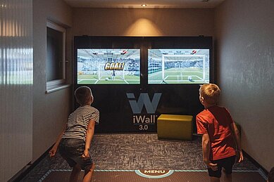 Zwei Jungs spielen Spiele auf der iWall des Familienhotels Huber in Südtirol