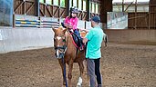 Ein Kind nimmt eine Ritstunde im Familienhotel Der Ponyhof in der Steiermark.