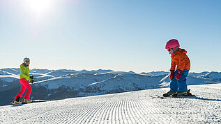 Familie in Kaernten im Winter beim Skifahren. Der Katschberg mit Sonne und blauem Himmel.