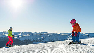 Familie in Kaernten im Winter beim Skifahren. Der Katschberg mit Sonne und blauem Himmel.