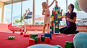 Kinder bauen aus Bauklötzen einen Turm im Happy-Club im Familienhotel Amiamo im Salzburger Land.