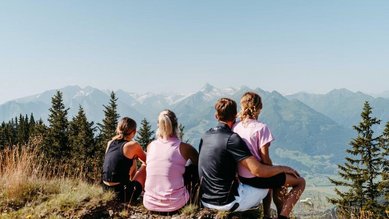 Familie genießt den Bergblick bei einer Wanderpause nahe dem Familienhotel Amiamo im Salzburger Land.