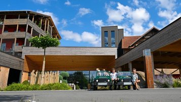 Zwei Jungen posieren in Kleinen Traktoren und Hunden vor dem Eingang des Familienhotels Ulrichshof im Bayerischenwald.