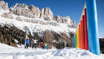 Glückliche Familie auf der Skipiste vor der Kulisse der verschneiten Dolomiten