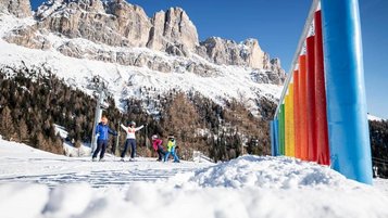 Glückliche Familie auf der Skipiste vor der Kulisse der verschneiten Dolomiten