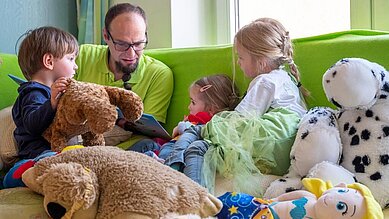 Betreuer liest Kinder ein Buch vor im Happy-Club im Familienhotel Mein Krug im Fichtelgebirge.