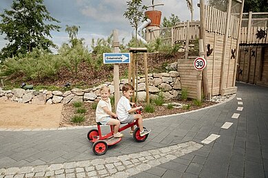 Geschwister fahren gemeinsam auf dem Dreirad im Familienhotel Seeklause an der Ostsee.