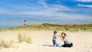 Mutter und Sohn spielen im Sand am deutschen Ostseestrand.