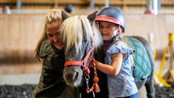 Ein Kind lernt reiten im Familienhotel Elldus Resort.