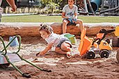 Kind spielt im Sandkasten auf dem Outdoor-Spielplatz des Familienhotels Huber in Südtirol