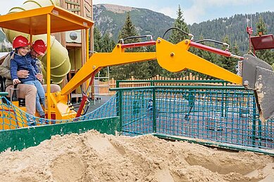 Vater und Tochter spielen auf dem Outdoor-Spielplatz vom Kaiserhof mit dem Bagger