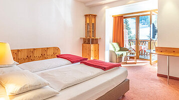 Ein Doppelzimmer mit Wohnbereich und Balkon im Familienhotel Kirchheimerhof in Kärnten.