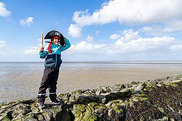 Kleiner Junge spielt im Piratenkostüm an der Nordsee.