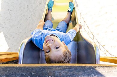 Junge rutscht die Rutsche auf dem Spielplatz vom Family Club Harz hinunter