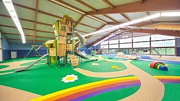 Großer Indoorspielplatz mit Kletterhaus und buntem Boden im Familienhotel Sonnenhügel in der Rhön.