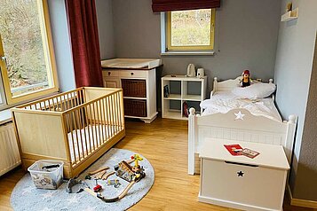 Liebevoll eingerichtetes Kinderzimmer mit einem Babybett, Wickeltisch und einer Spielecke im Family Club Harz.