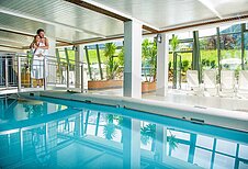 Schwimmbad mit einer Brücke und Panoramaausblick auf die Landschaft des Familienhotels Sonngastein in Bad Gastein.