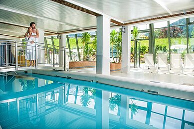 Schwimmbad mit einer Brücke und Panoramaausblick auf die Landschaft des Familienhotels Sonngastein in Bad Gastein.