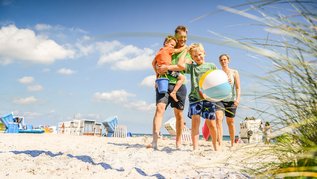 Familie spaziert am Strand an der Ostsee entlang.