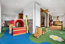 Großzügiger Indoor-Spielraum mit buntem Boden, Holzspielgeräten und Kletterelementen für Kinder im Hotel Engel im Schwarzwald