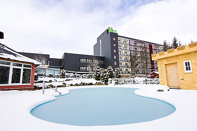 Die Hotelanlage vom Familotel Am Rennsteig im Winter mit zugefrorenem Außenpool