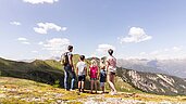 Familie in den Bergen macht eine Pause mit toller Aussicht in der Nähe des Familienhotels Almfamilyhotel Scherer in Tirol.