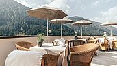 Sonnenterrasse mit Rattanmöbeln und Sonnenschirmen im Familienhotel Engel Gourmet & Spa in Südtirol.