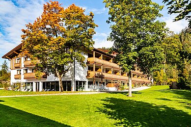 Außenansicht vom Familienhotel Das Bayrischzell im Herbst mit Parkanlage und Gartengestaltung.