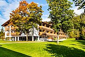 Außenansicht vom Familienhotel Das Bayrischzell im Herbst mit Parkanlage und Gartengestaltung.