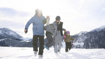 Gäste des Familienhotels Das Bayrischzell in Bayern sind mit ihren Kinder am Sudelfeld Skifahren.